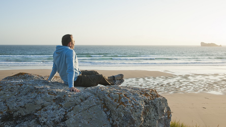 A man on a rock at the beach A man on a rock at the beach