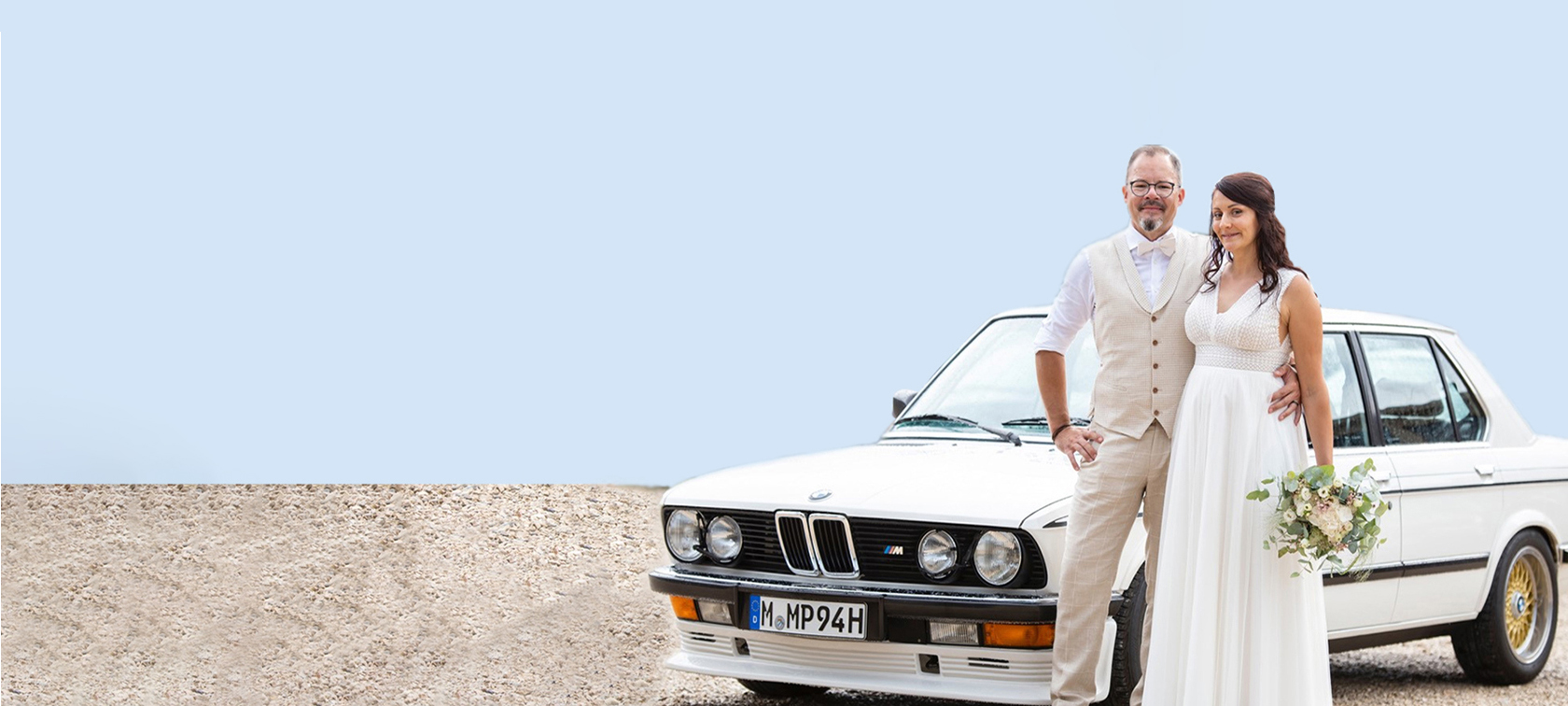 Hochzeitspaar steht vor BMW Auto