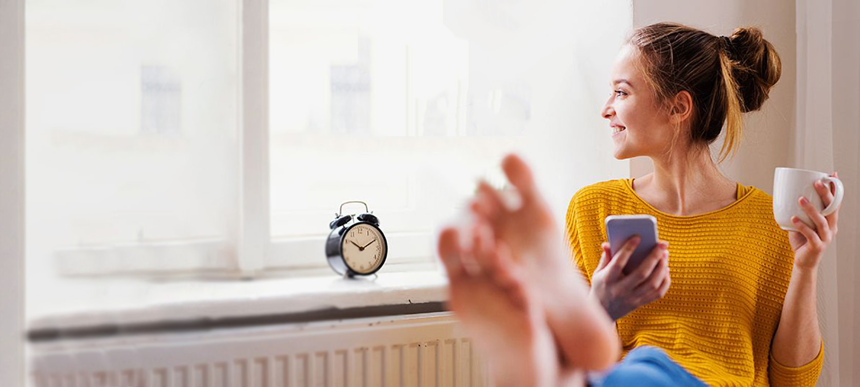 Frau sitzt im Wohnzimmer am Handy.