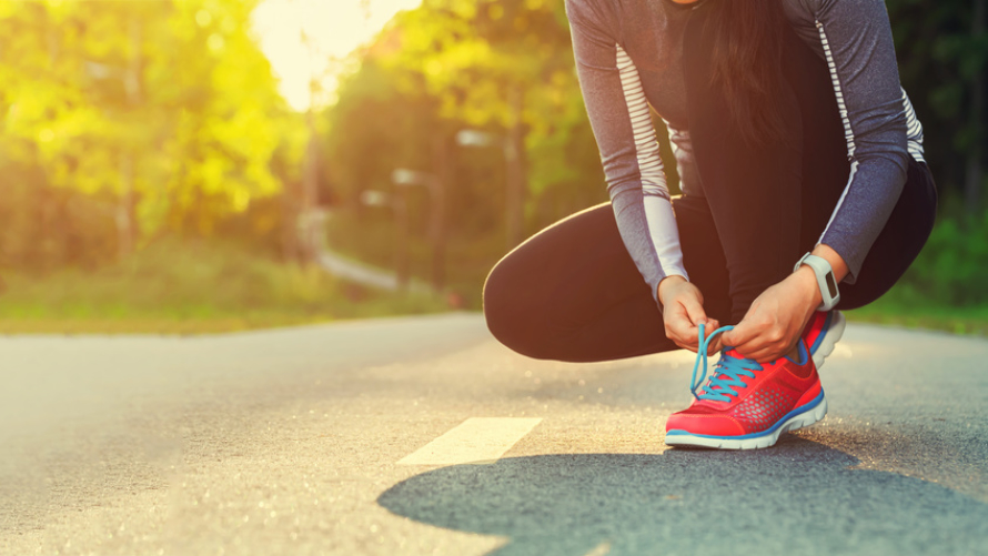 Frau bindet sich ihre Laufschuhe zu Frau bindet sich ihre Laufschuhe zu