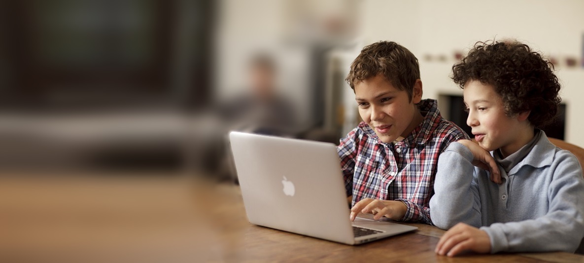 Zwei Kinder am Laptop Zwei Kinder sitzen an einem Tisch und schauen in einen Laptop