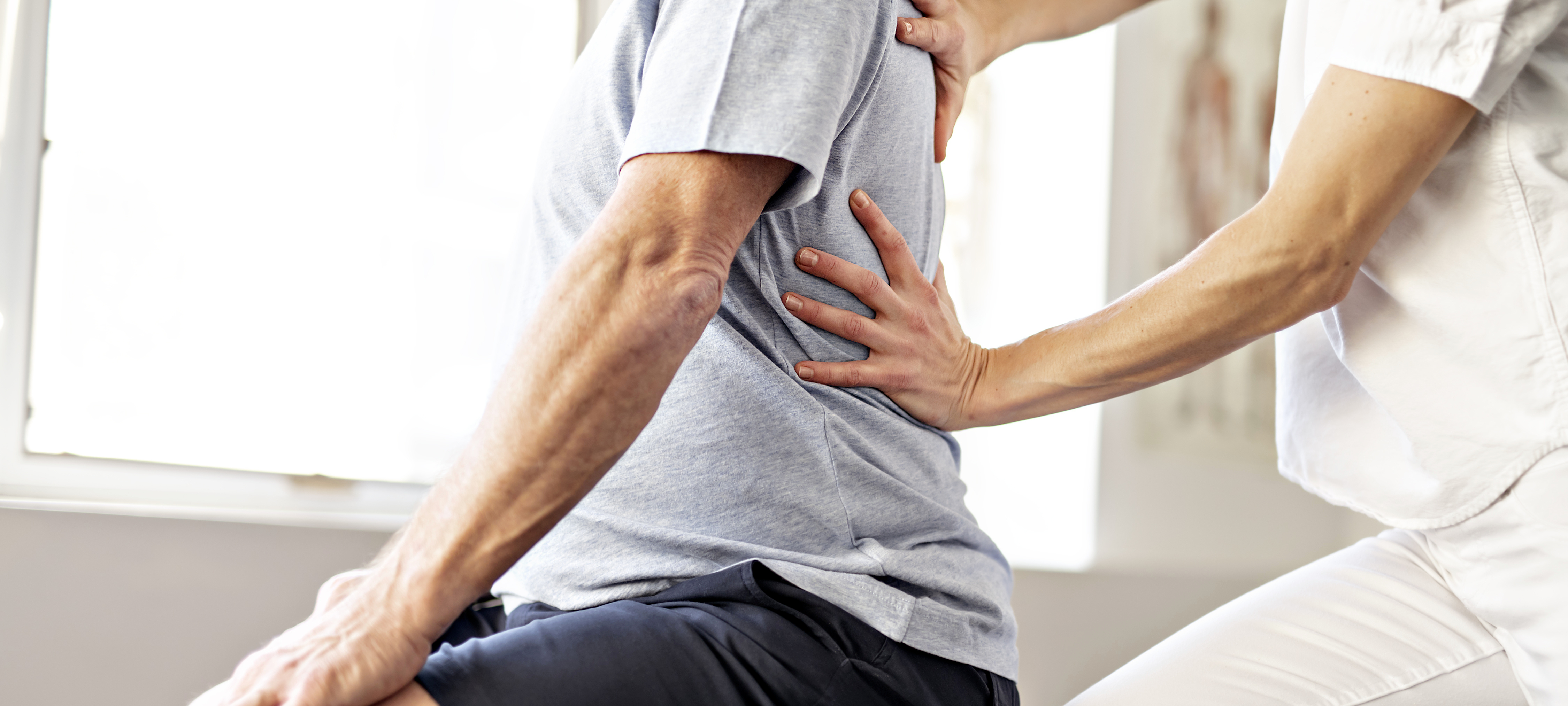 Physiotherapeut stabilisiert Rücken eines Patienten Physiotherapeut stabilisiert Rücken eines Patienten