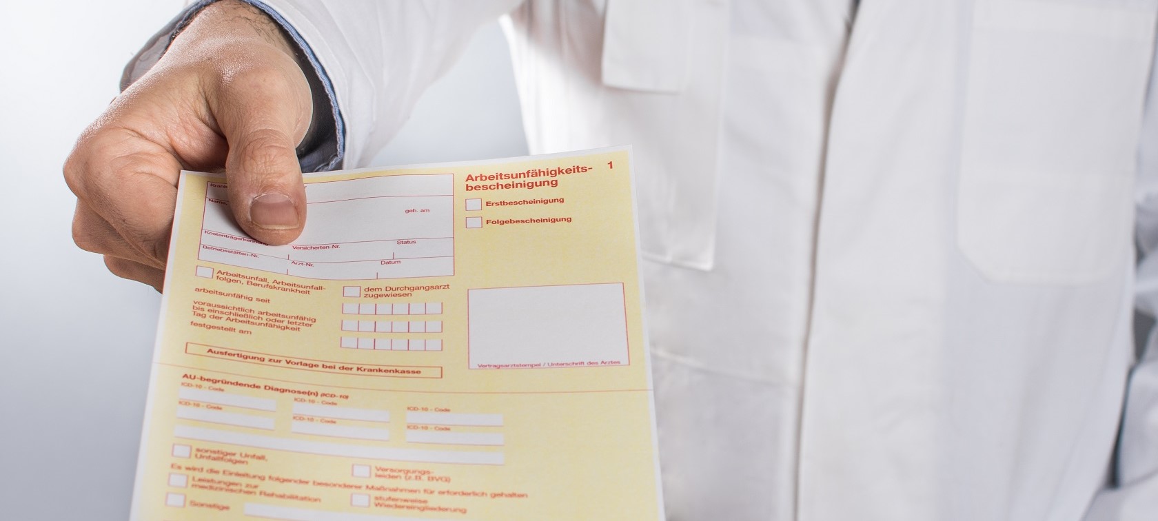 Arzt überreicht Arbeitsunfähigkeitsbescheinigung Hand eines männlichen Arztes im Kittel überreicht Arbeitsunfähigkeitsbescheinigung
