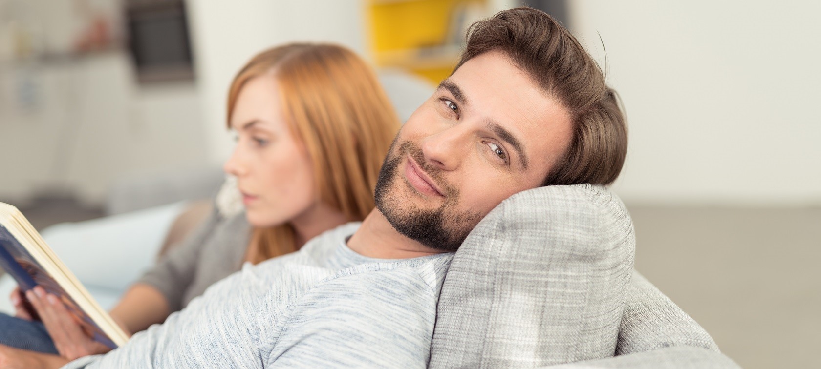 Pärchen auf dem Sofa Ein Pärchen sitzt auf dem Sofa und der Mann lächelt in die Kamera
