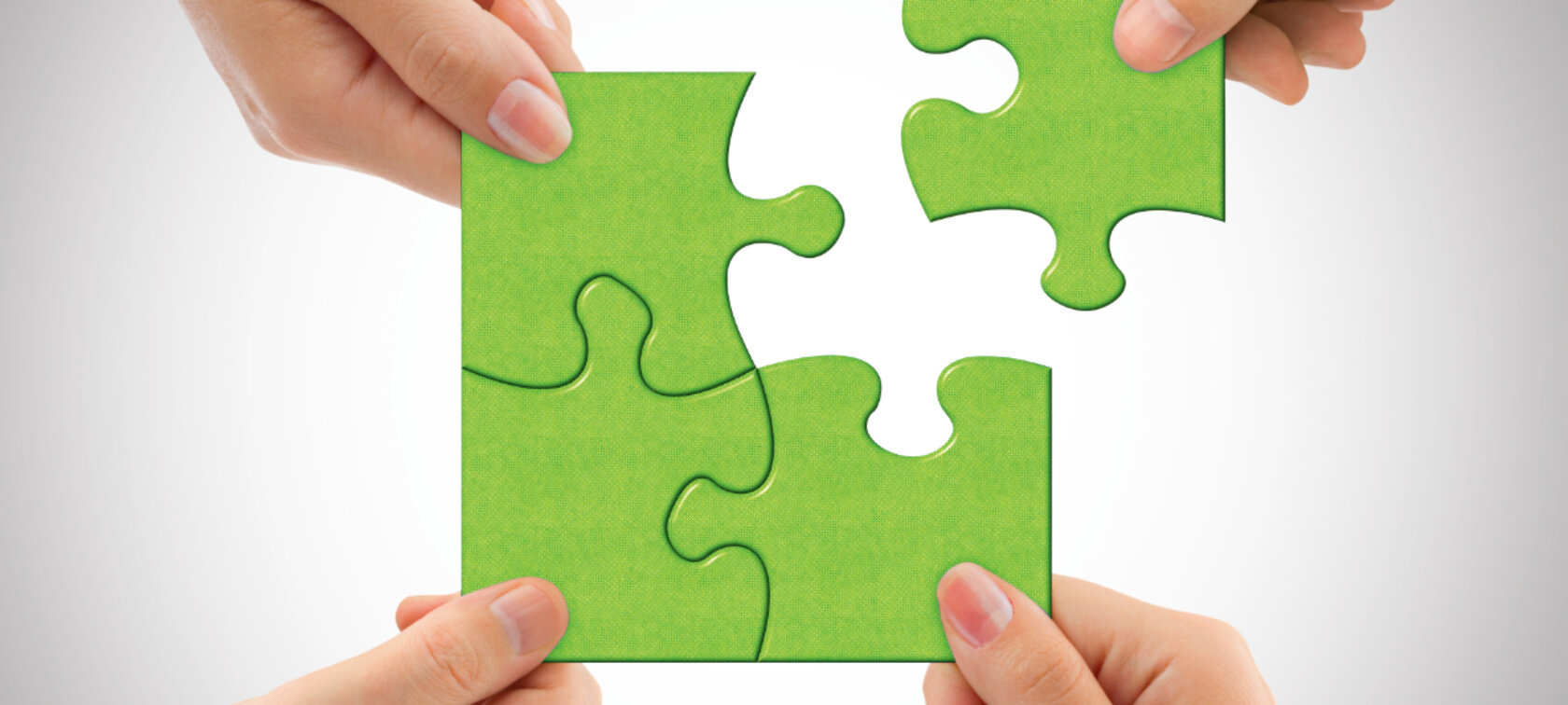Grünes Puzzle Vier Hände halten 4 Puzzlestücke