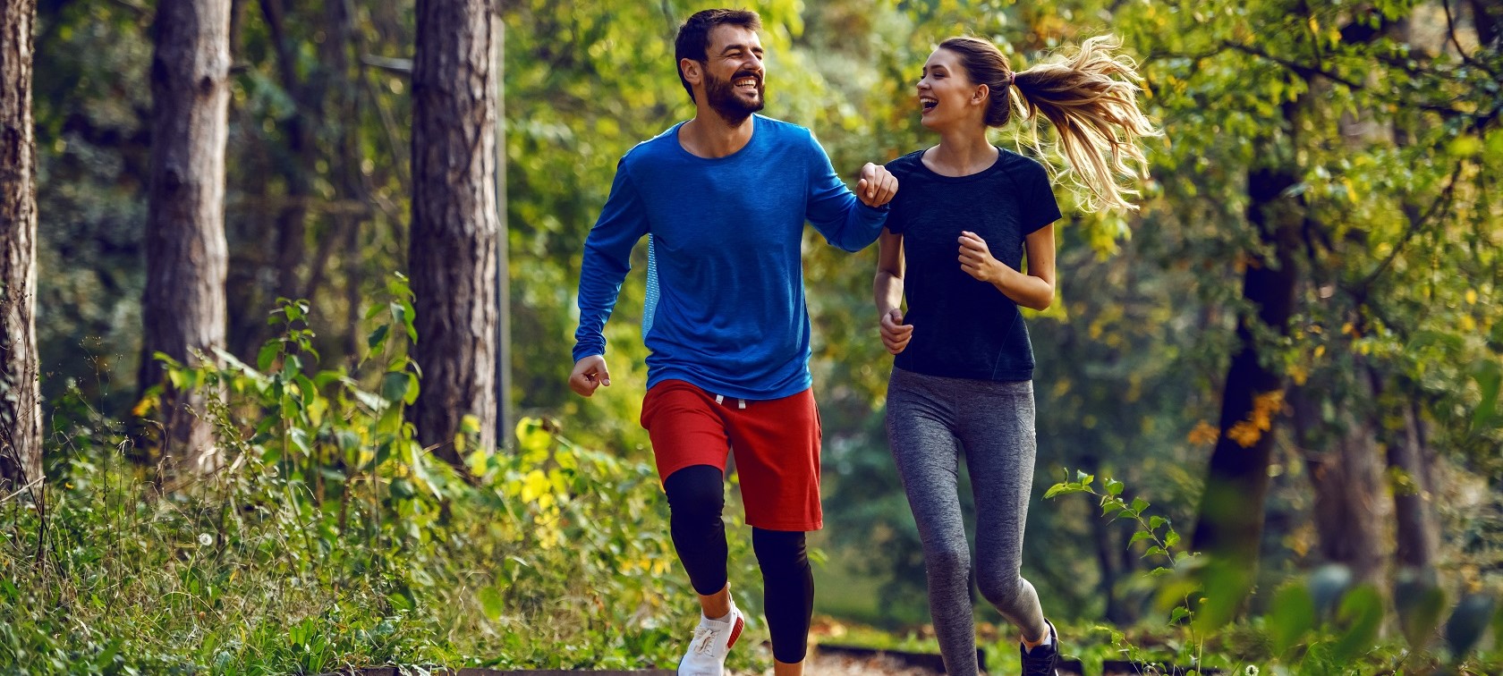 Paar joggt Paar joggt fröhlich lachend im Wald