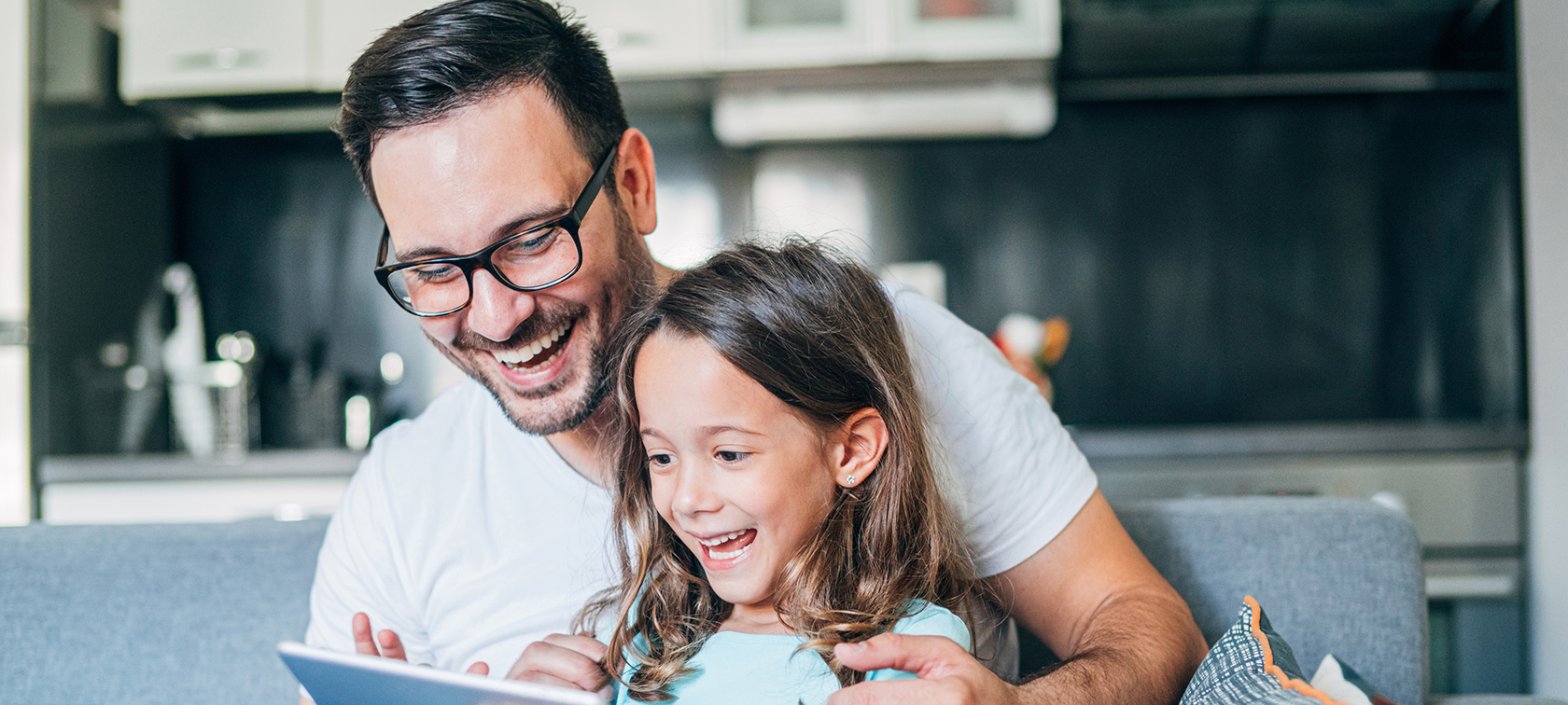 Vater und Tochter sitzen auch Couch und schauen auf Tablet. Vater und Tochter sitzen auch Couch und schauen auf Tablet.
